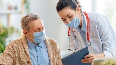 Doctor and patient wearing masks looking at paperwork