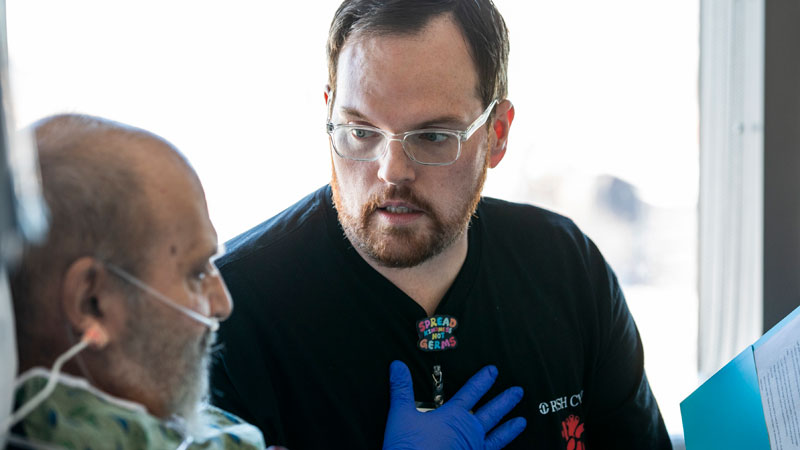 A Rush nurse speaks with a patient in a hospital bed