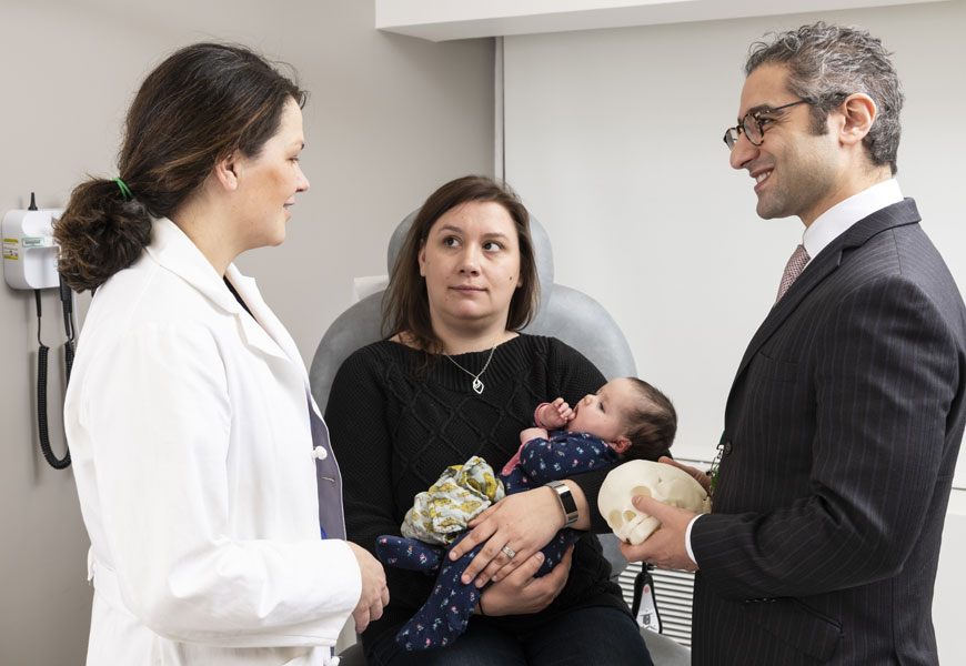 two doctors talking to mother holding baby