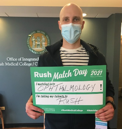Student holding up sign with text: Rush Match Day 2021 - I matched into Ophthalmology - I'm taking my talents to Rush