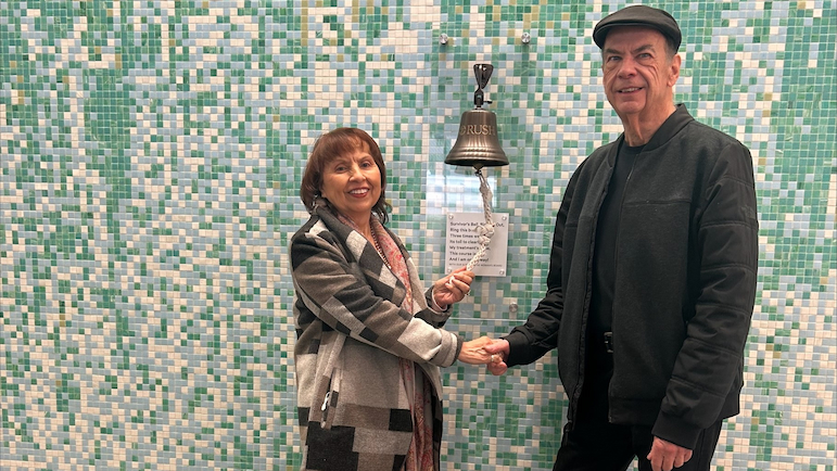 Alicia Wieder pulls the rope on the survivor's bell at Rush with one hand while holding hands with another person.