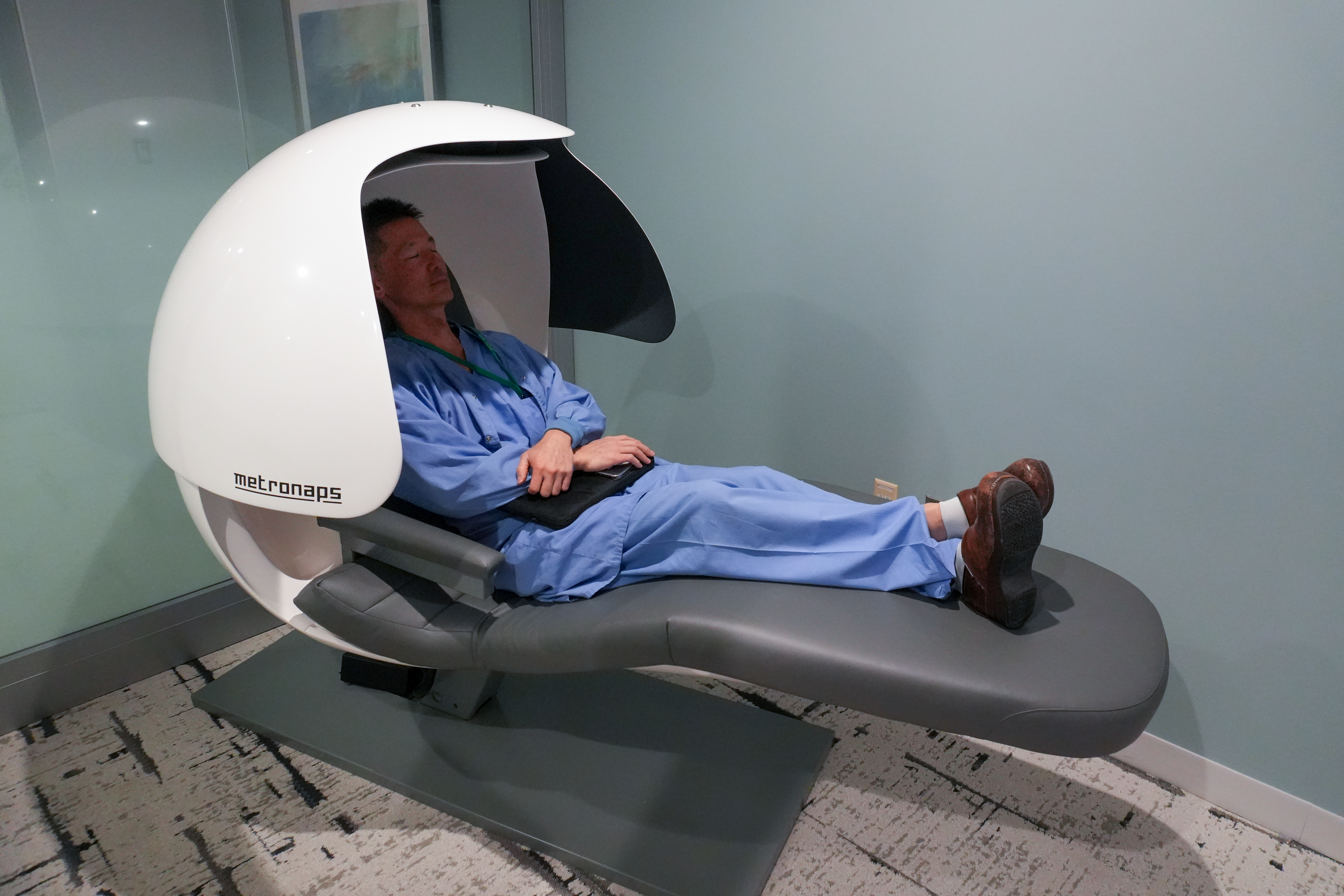 A man in blue scrubs relaxes in a pod-like chair