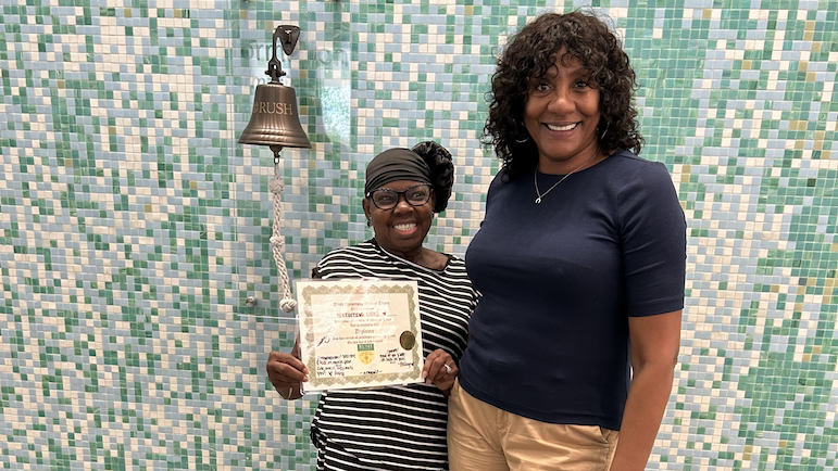 Alicia Wieder pulls the rope on the survivor's bell at Rush with one hand while holding hands with another person.