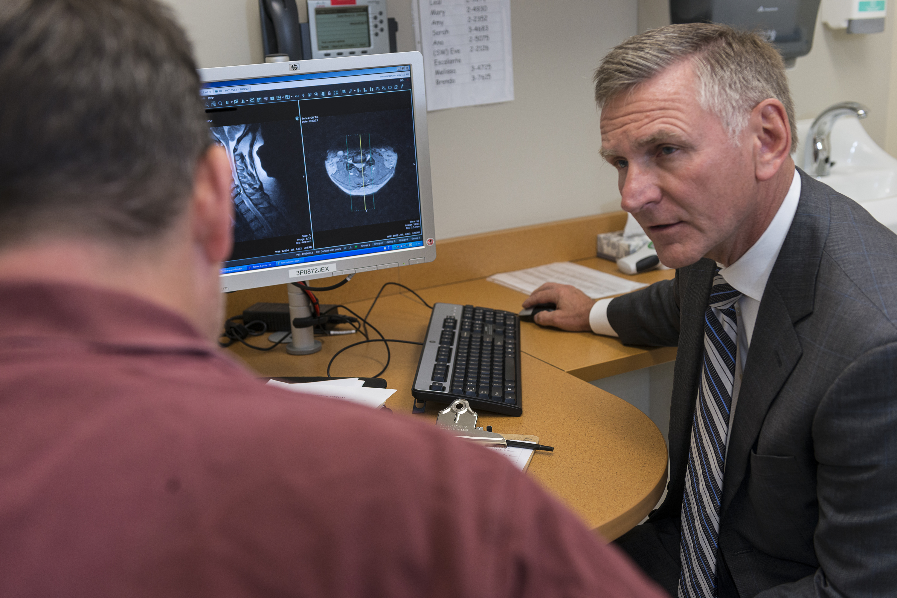 Dr. Fessler reviews spinal imaging with a man at a computer workstation in a clinical office.