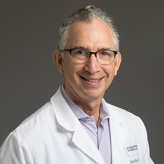 david ansell dressed in white coat posed in front of gray background