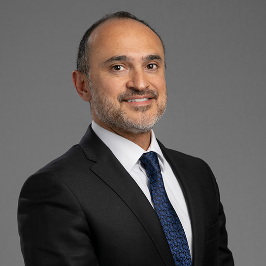 faisal hasan posed in front of a gray background