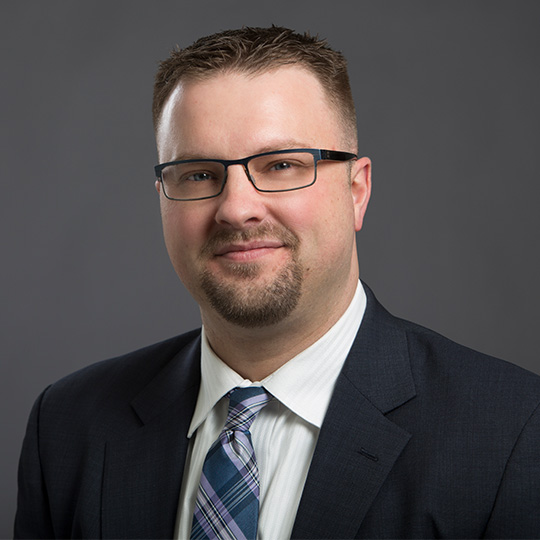 j brady scott posed in front of a gray background