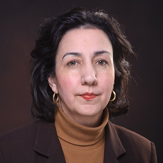 neelum aggarwal posed in front of a brown background