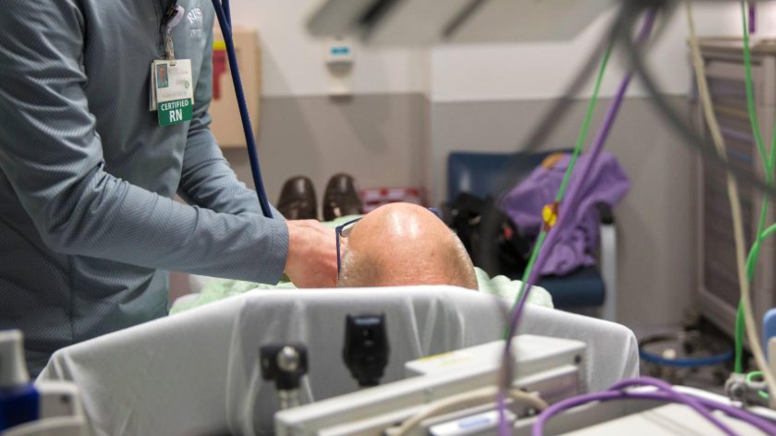 Close-up of a nurse tending to a patient lying in a hospital bed
