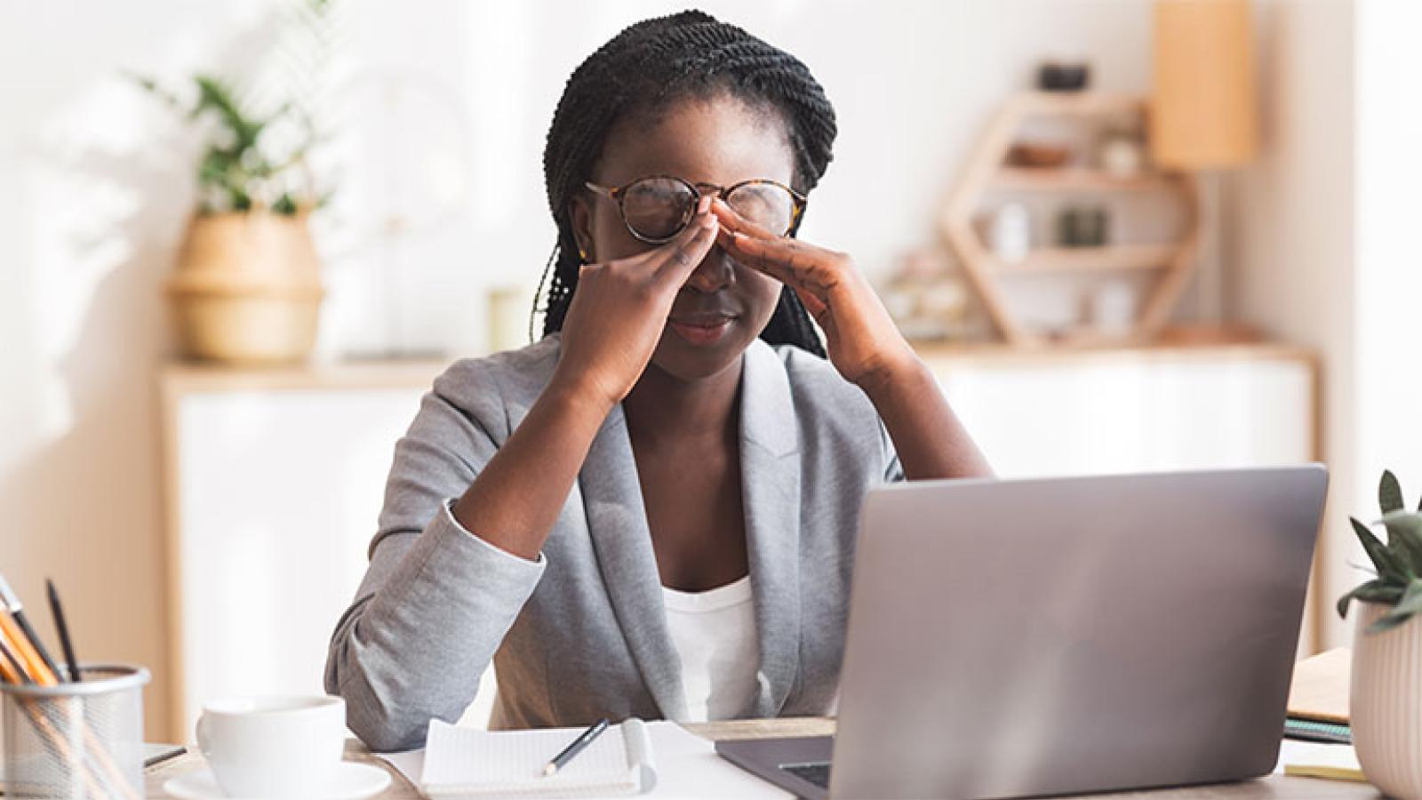 Woman at desk massaging nose bridge