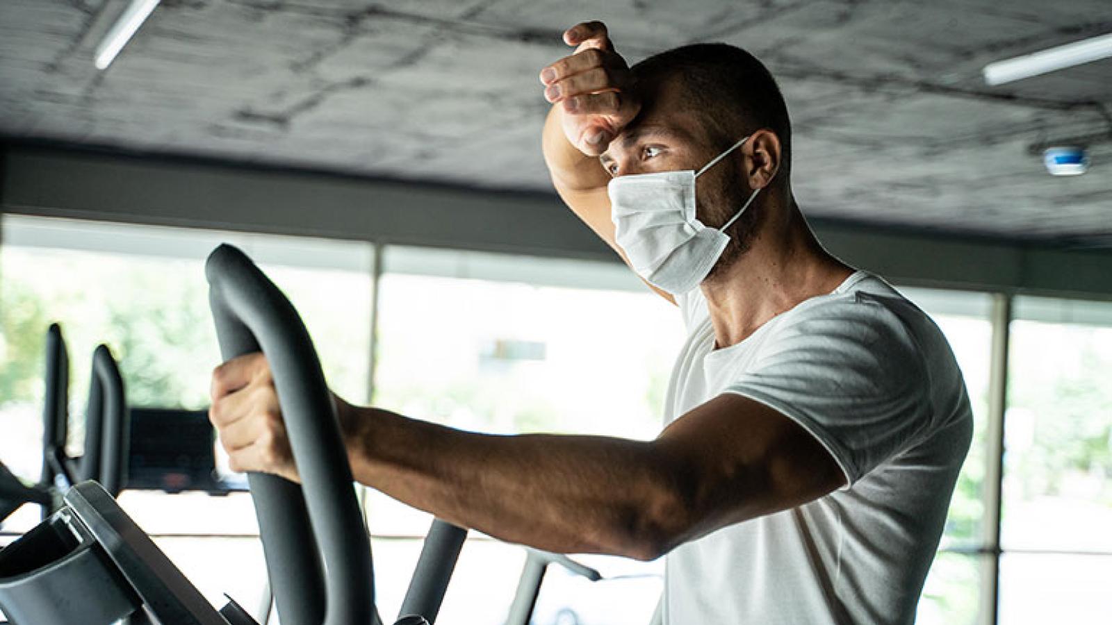 Man wiping forehead with hand while exercising