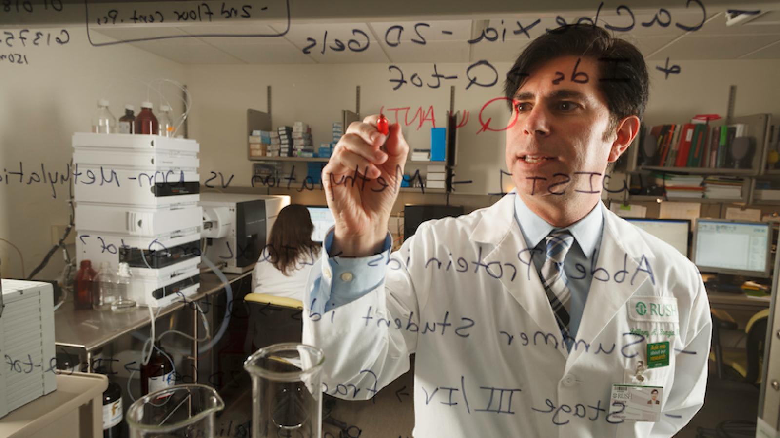 Jeffrey Borgia, PhD, writes from the other side of a clear surface.