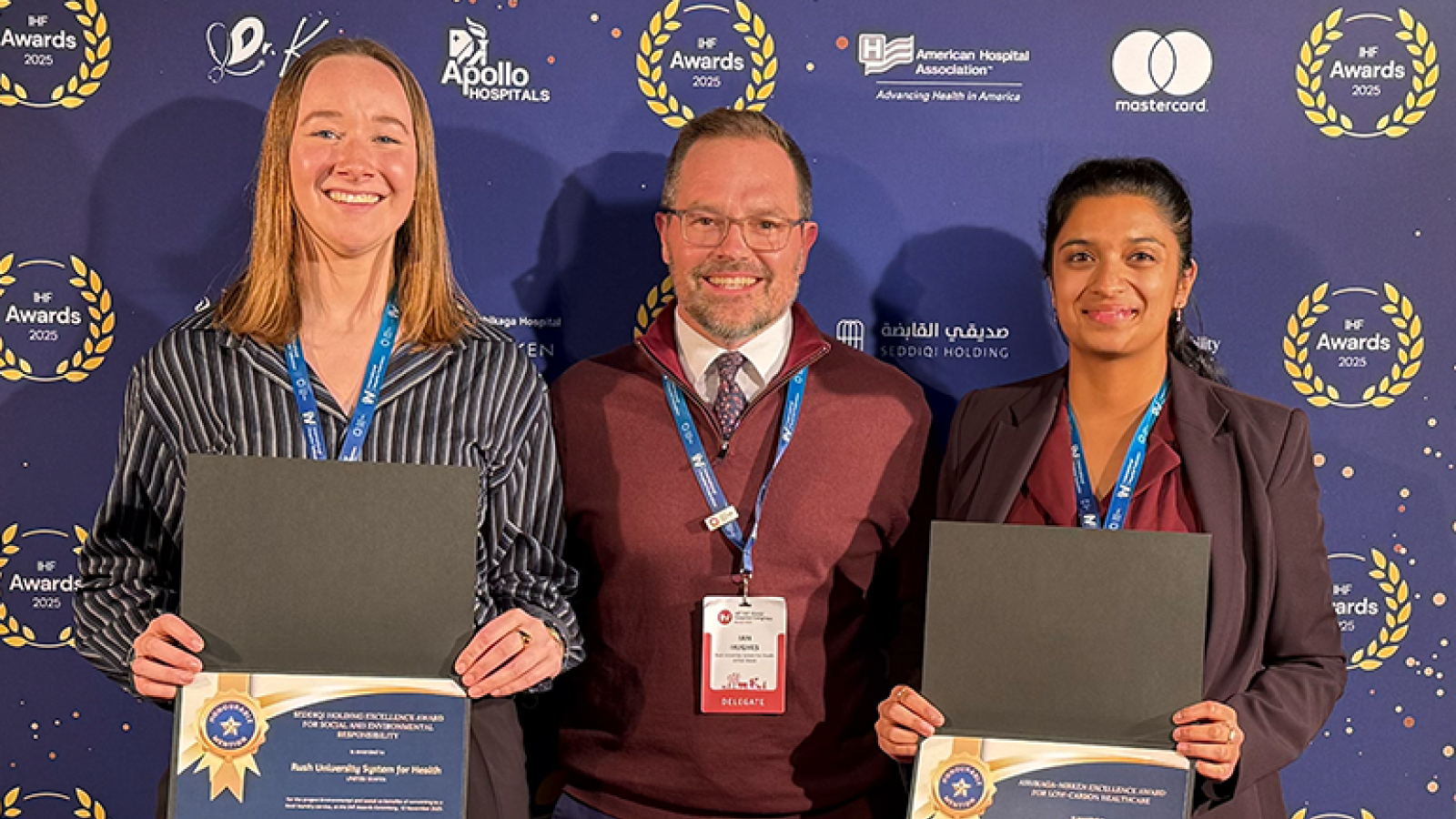 Rush's environmental sustainability team posing in front of a step-and-repeat holding awards.