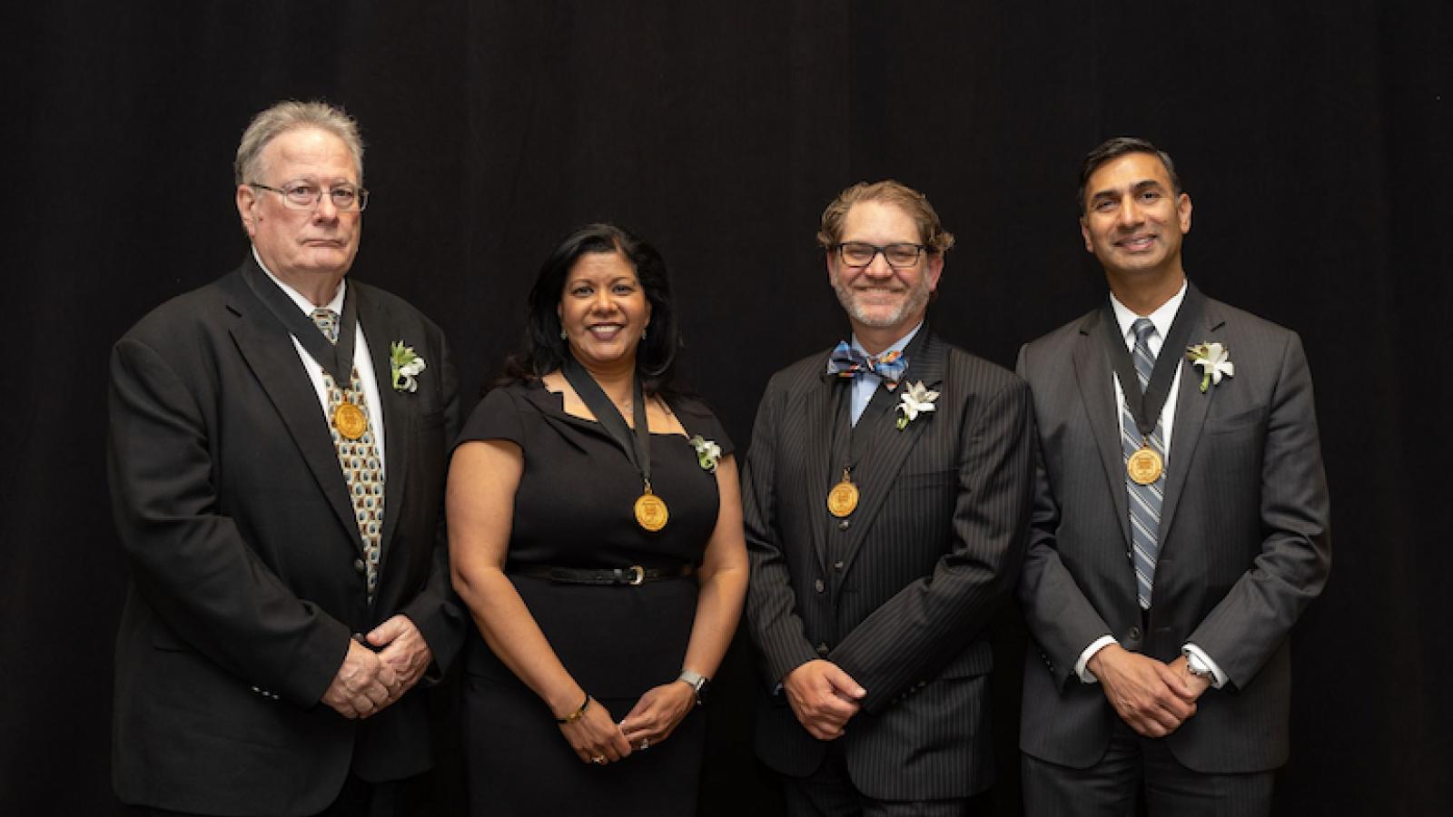 Standing, left to right, in front of a black background, are Robert J. McCarthy, Rupa Sanghani, Jason S. Turner and Pete S. Batra.
