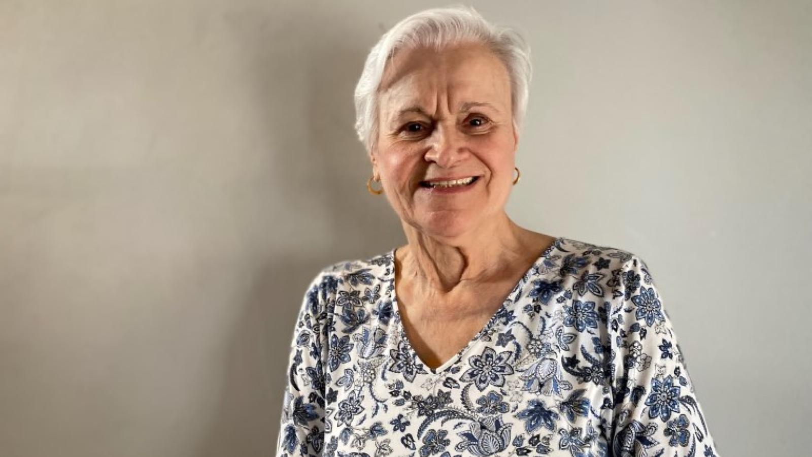 Janet smiles in front of a neutral background.
