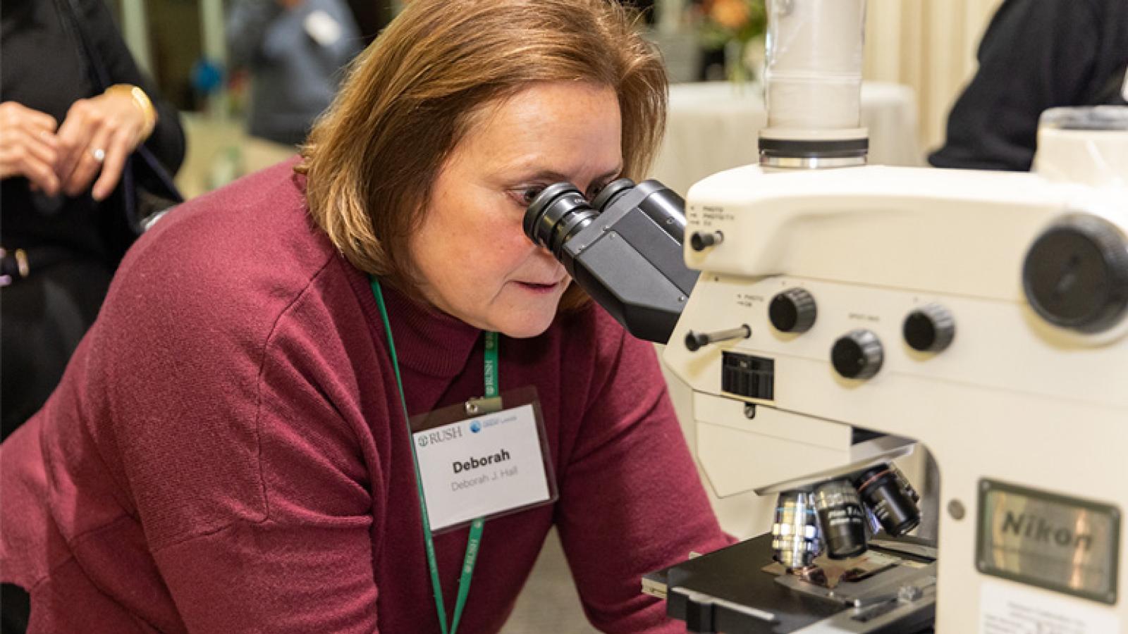 Deborah Hall looks into a microscope.