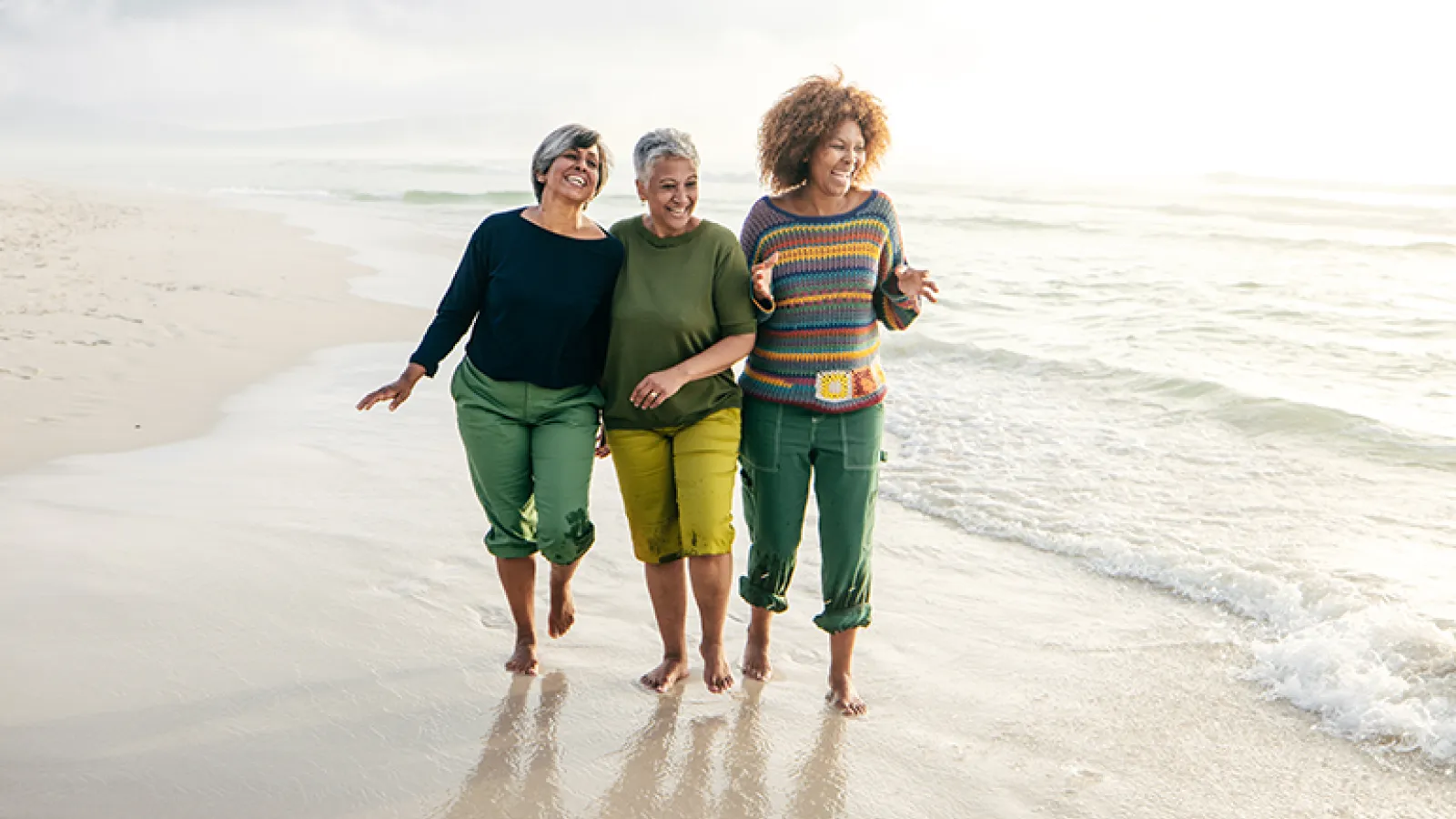 Three women walk on the beach together