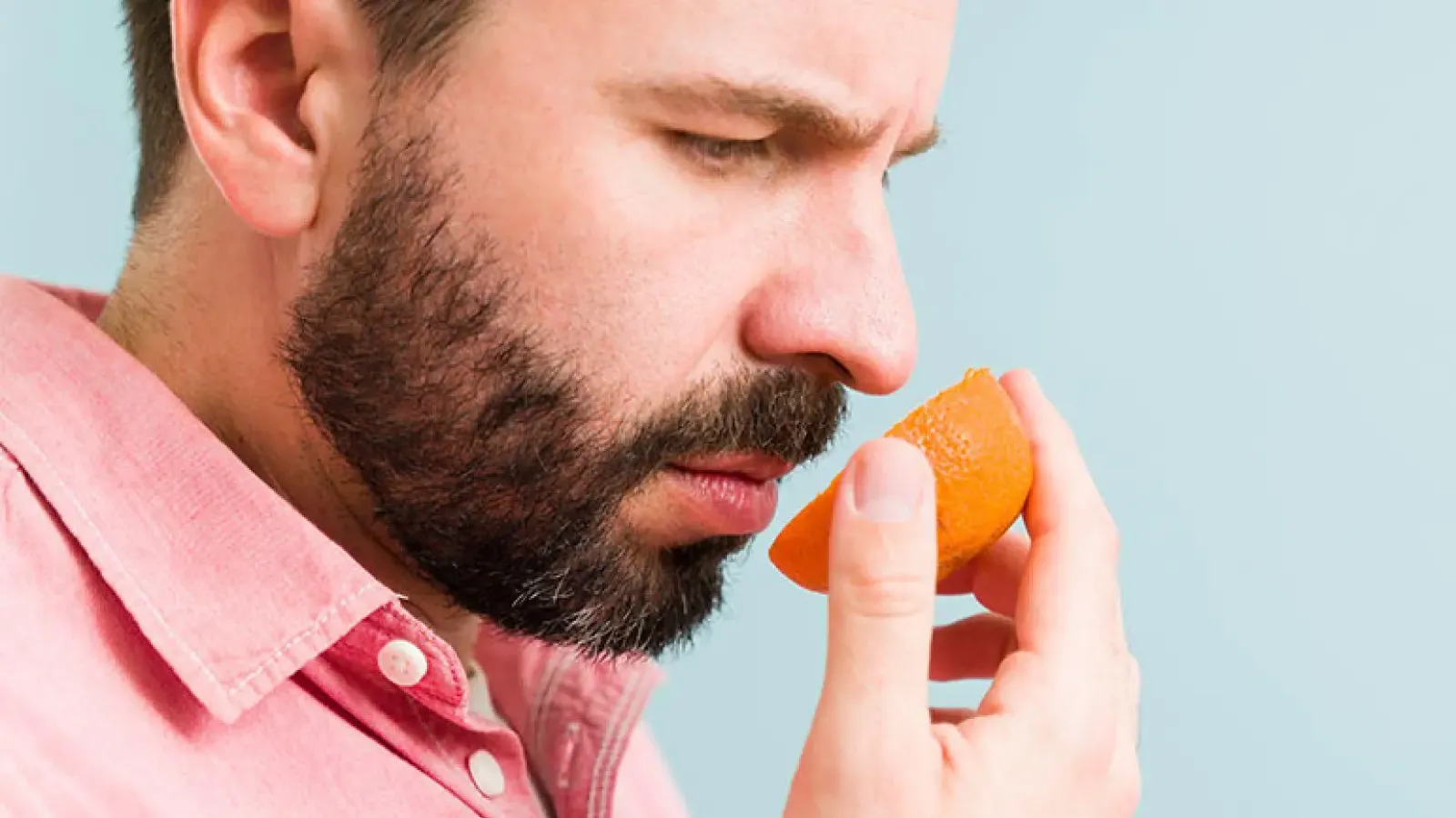 A person smelling a sliced piece or orange