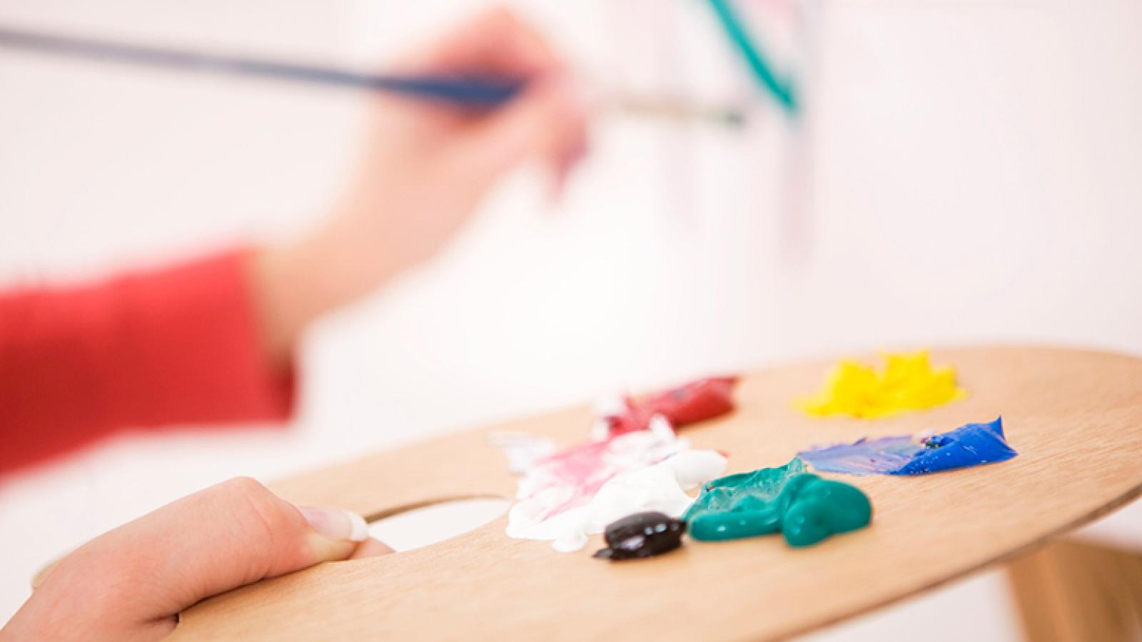 person painting, holding paint palette