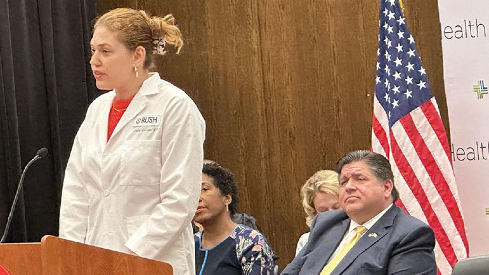 Dr. Laura Laursen speaks. Gov. J.B. Pritzker in the background