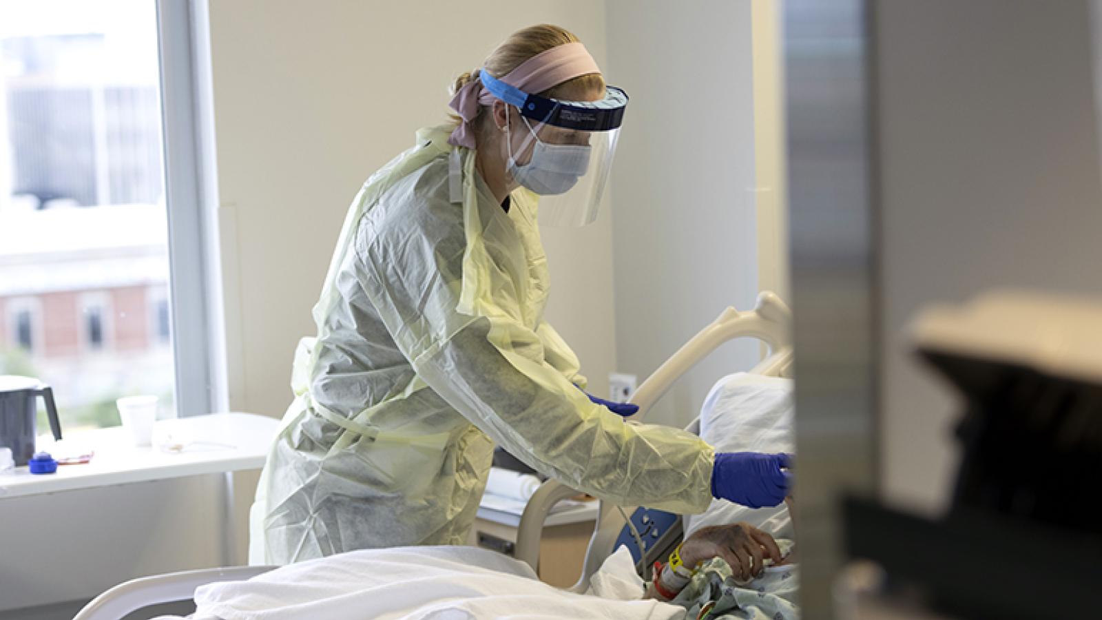 A nurse tends to a patient in a hospital bed.