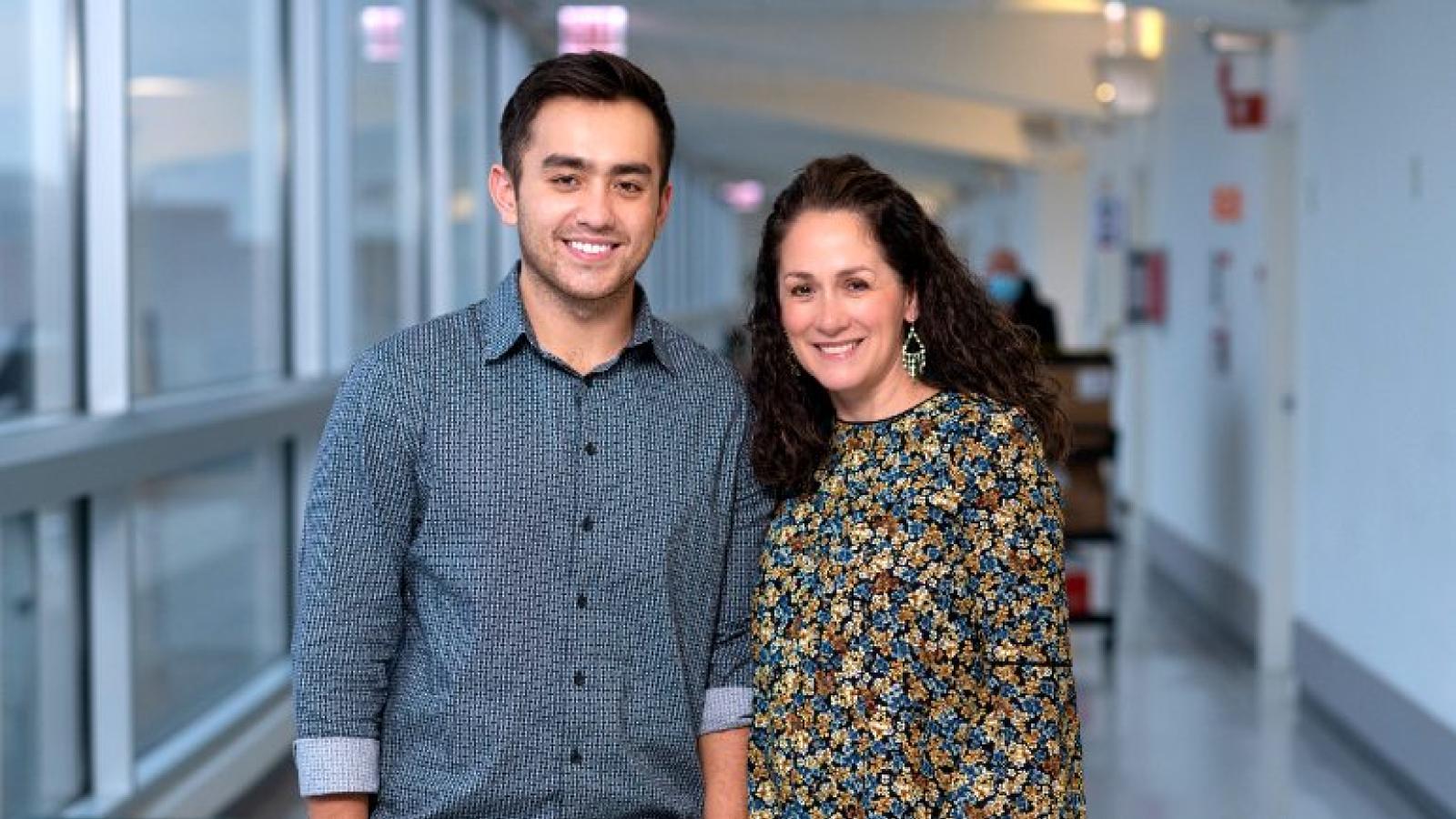 Two people standing together smiling in a hallway