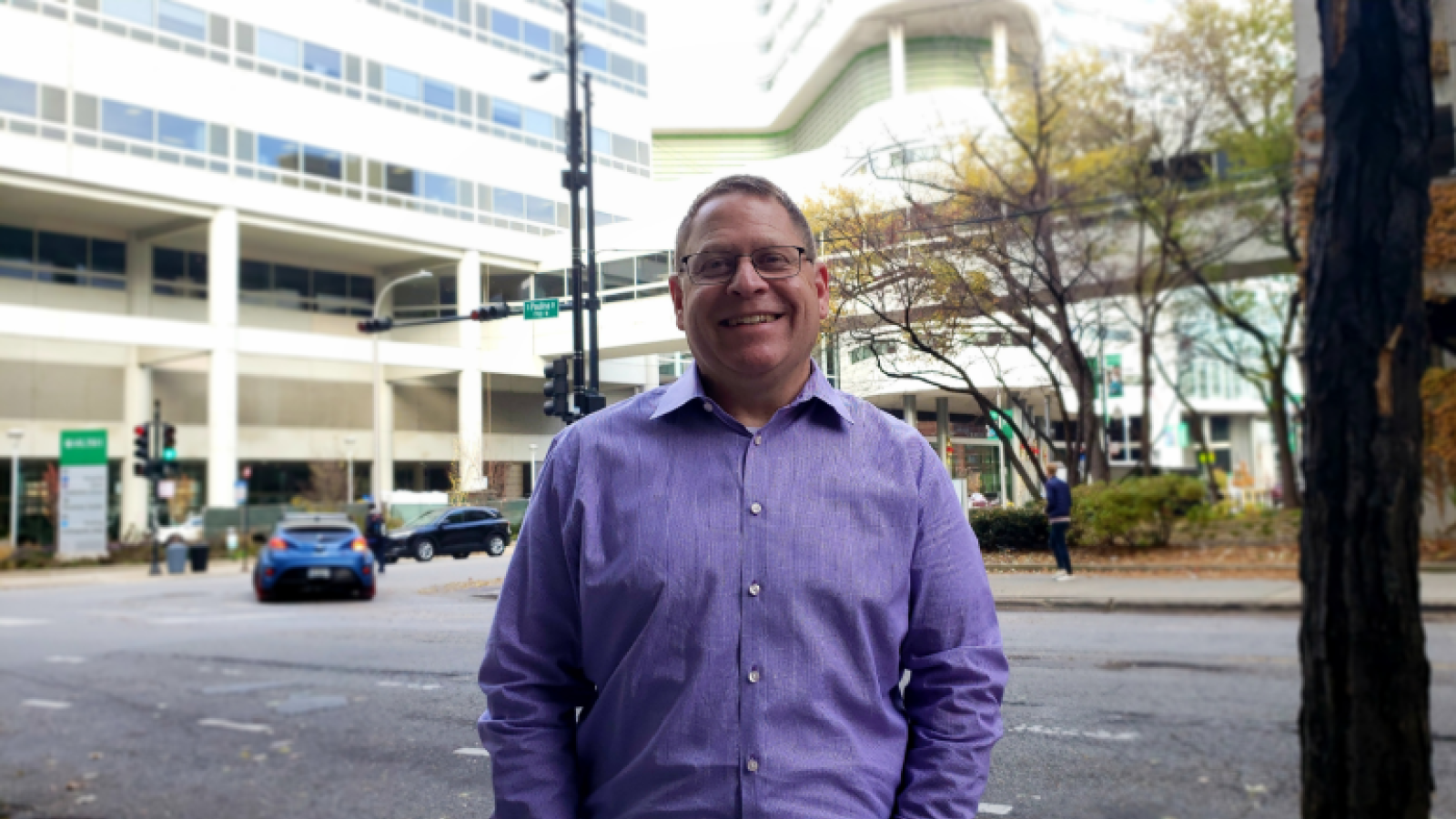 Patient David Baron stands outside of RUSH University Medical Center on a sunny day.