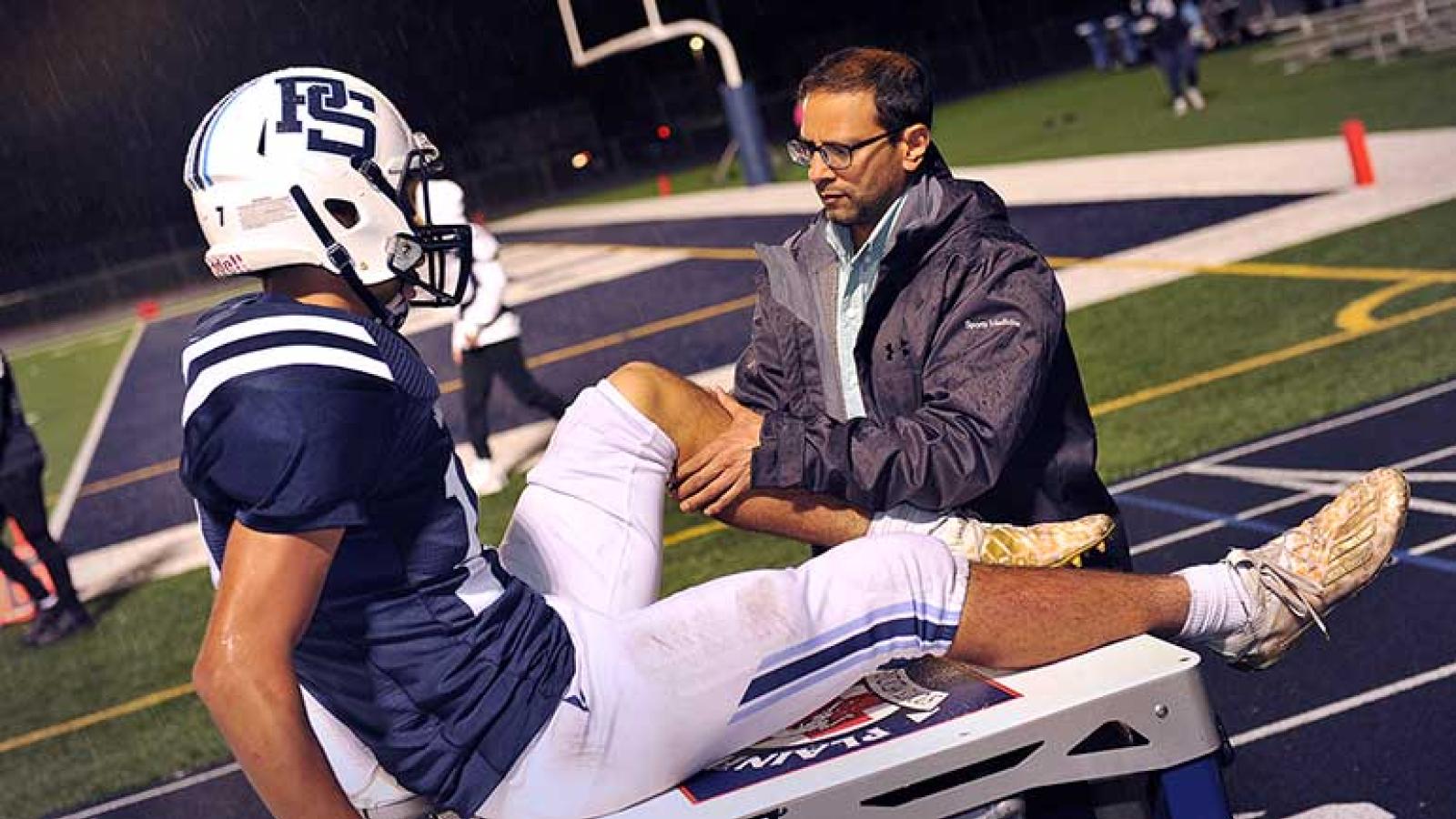 Deepak Patel, MD, evaluating football player