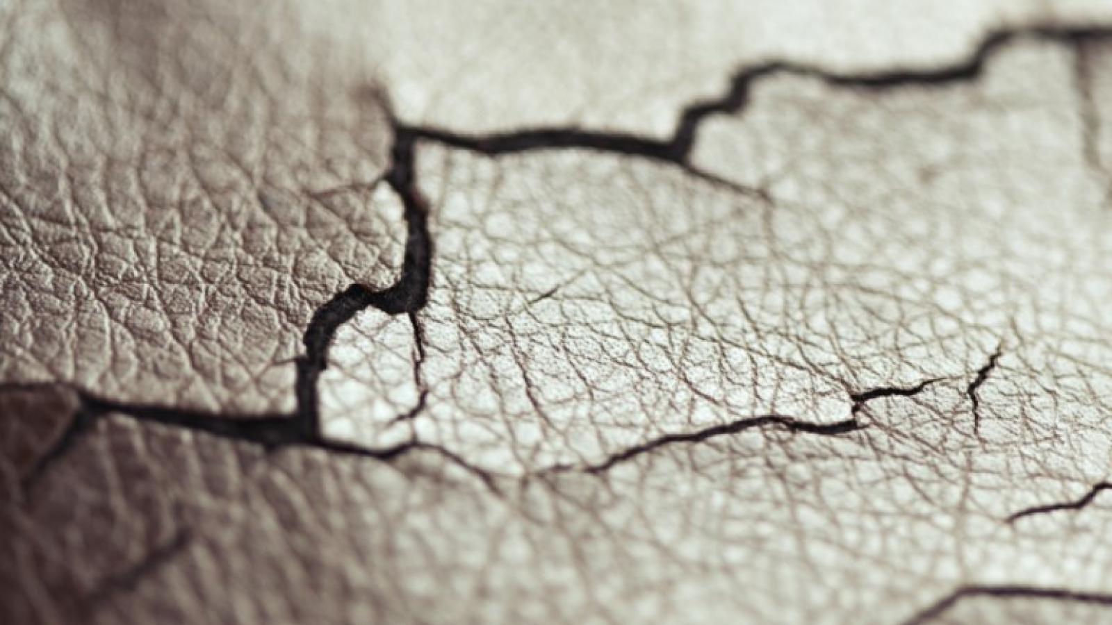 A closeup of gray faux leather that is dry and cracked.