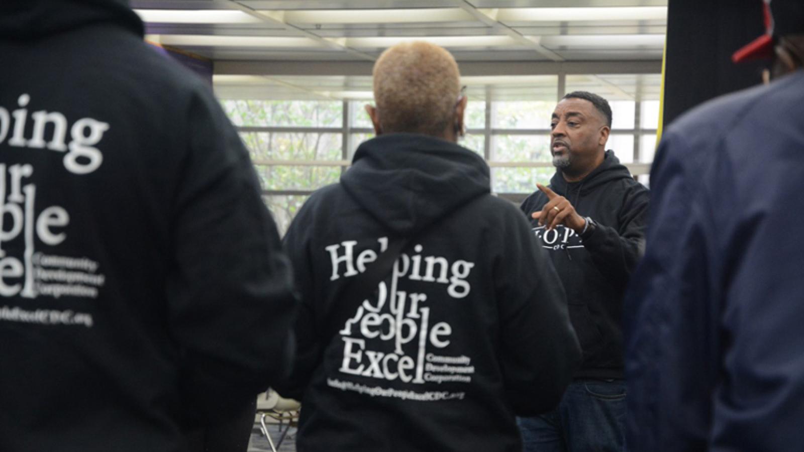 Pastor Steve Epting, in a black hoodie, speaks to people around him.