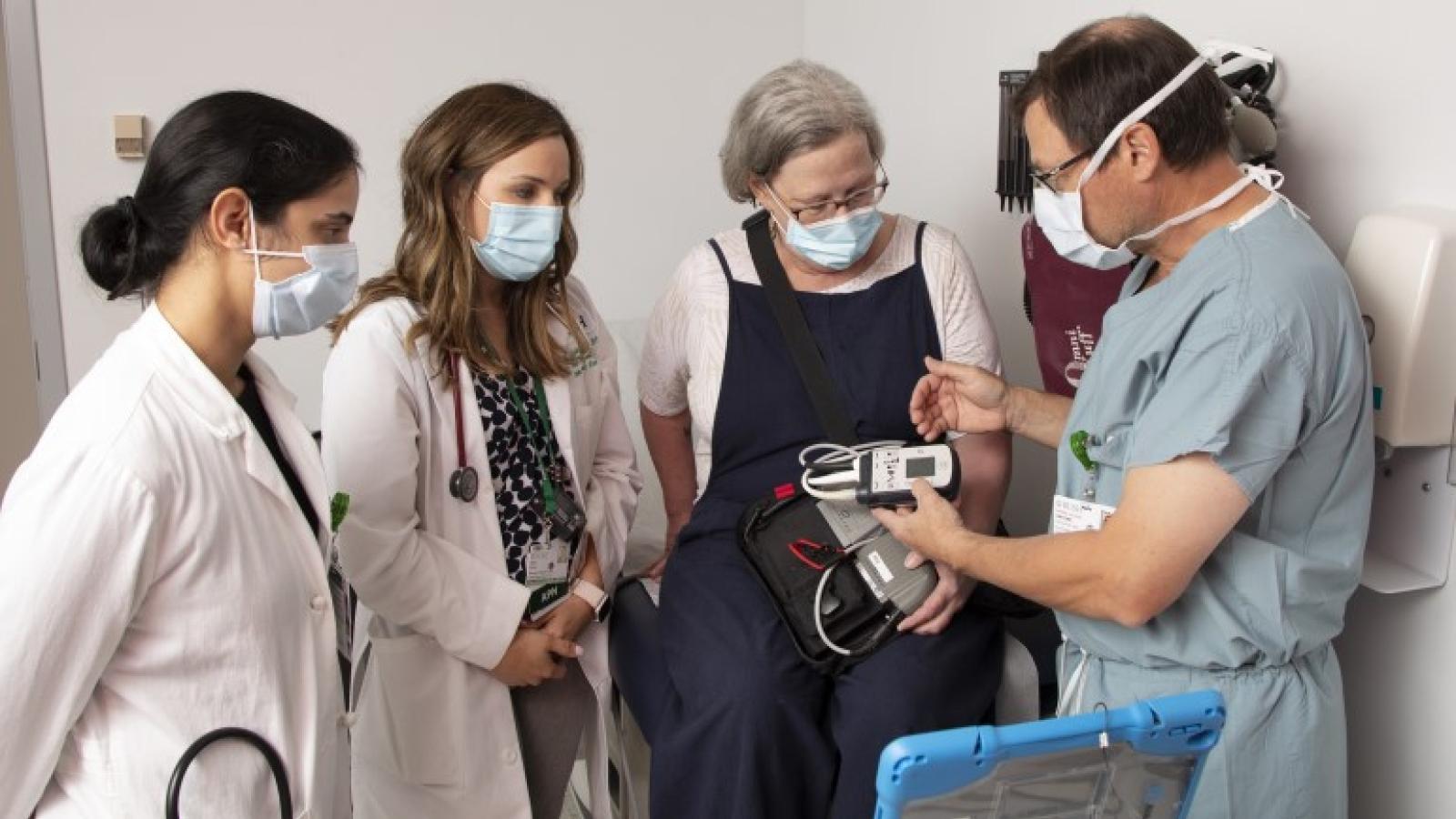 Tatooles, MD, shows a patient a ventricular assist device as Joshi, MD, and Shanklin, NP, look on.