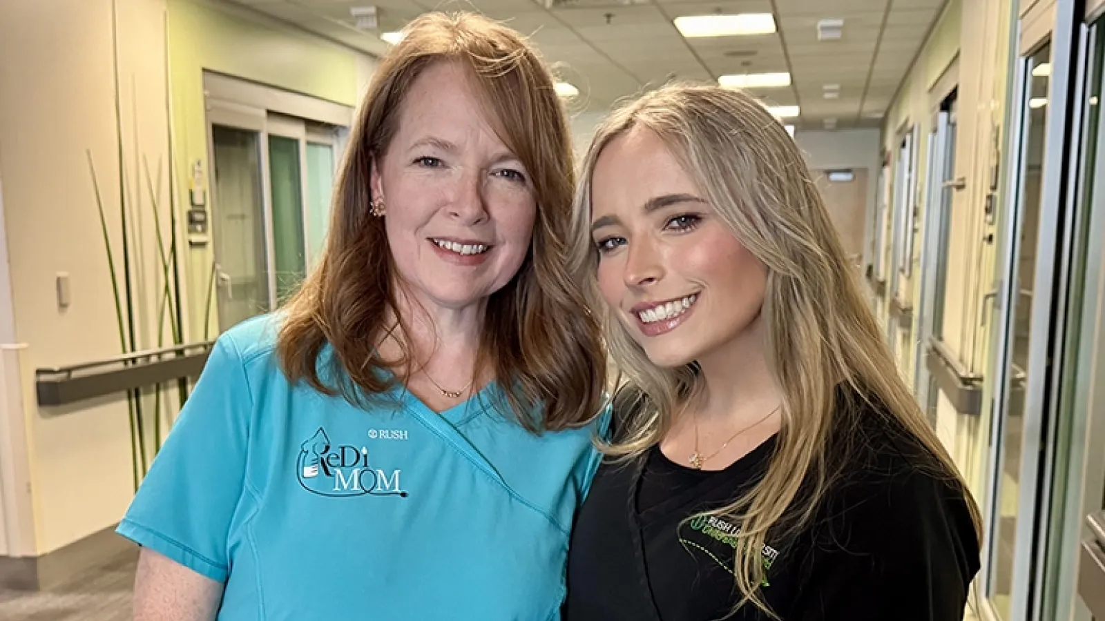 An older woman and a younger woman smile at the camera inside the NICU