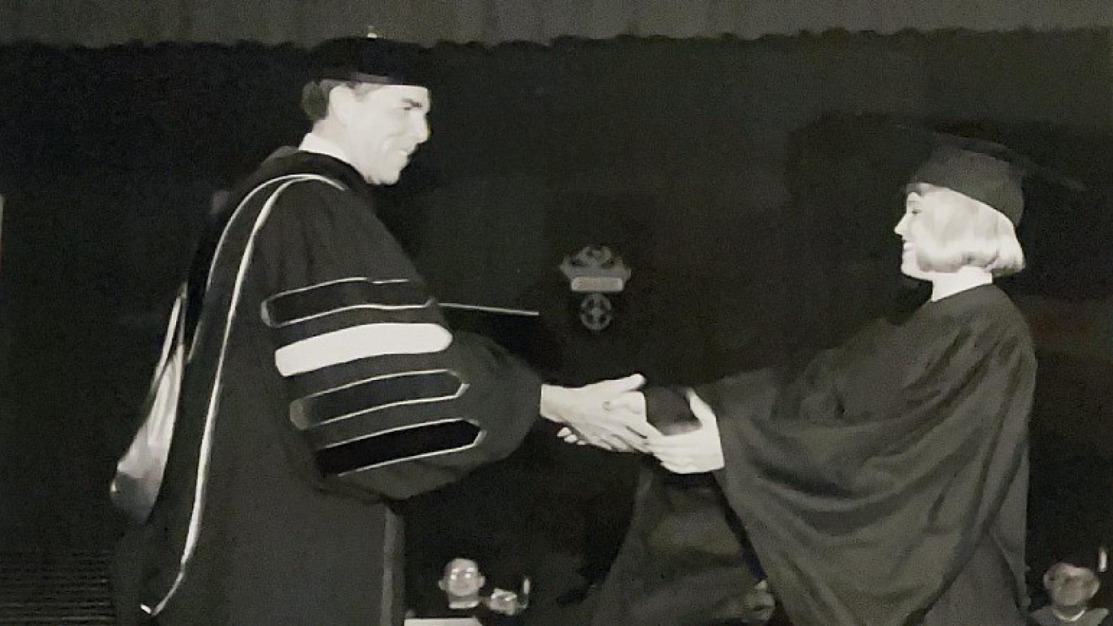 Black and white photo of a graduate receiving a diploma