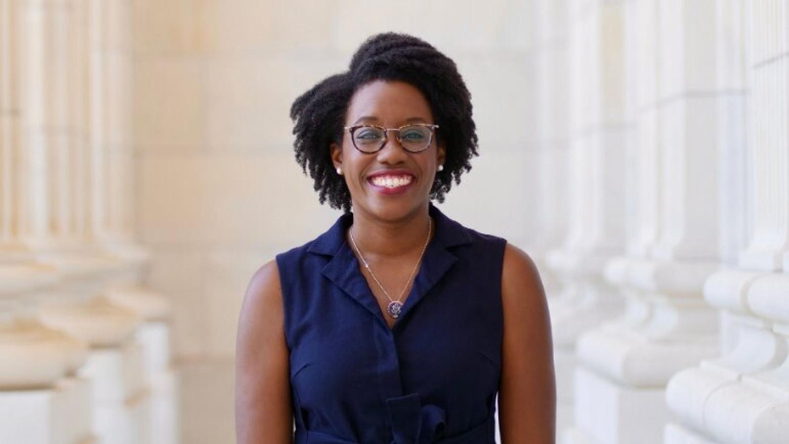 A smiling woman in front of tall architectural columns