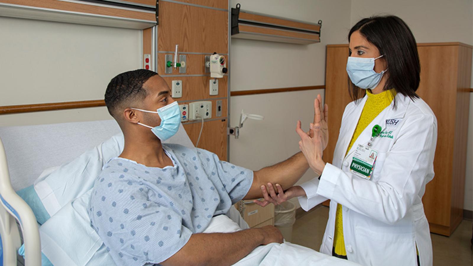 RUSH physician assesses RUSH patient sitting upright in hospital bed