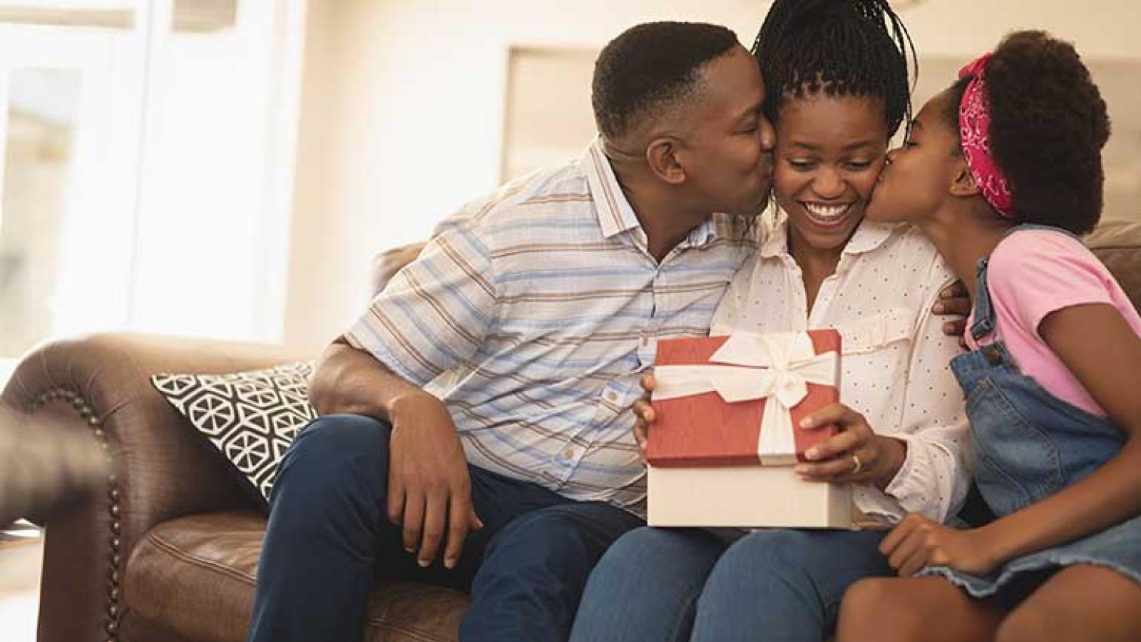 Father and daughter kissing mother on cheek