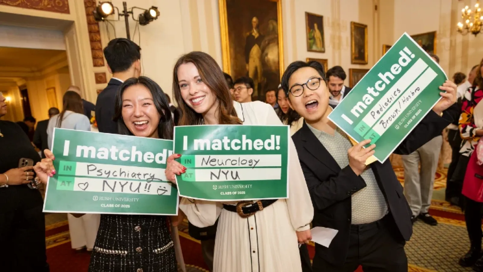 Three people in a formal room, smiling and holding signs that say I Matched!
