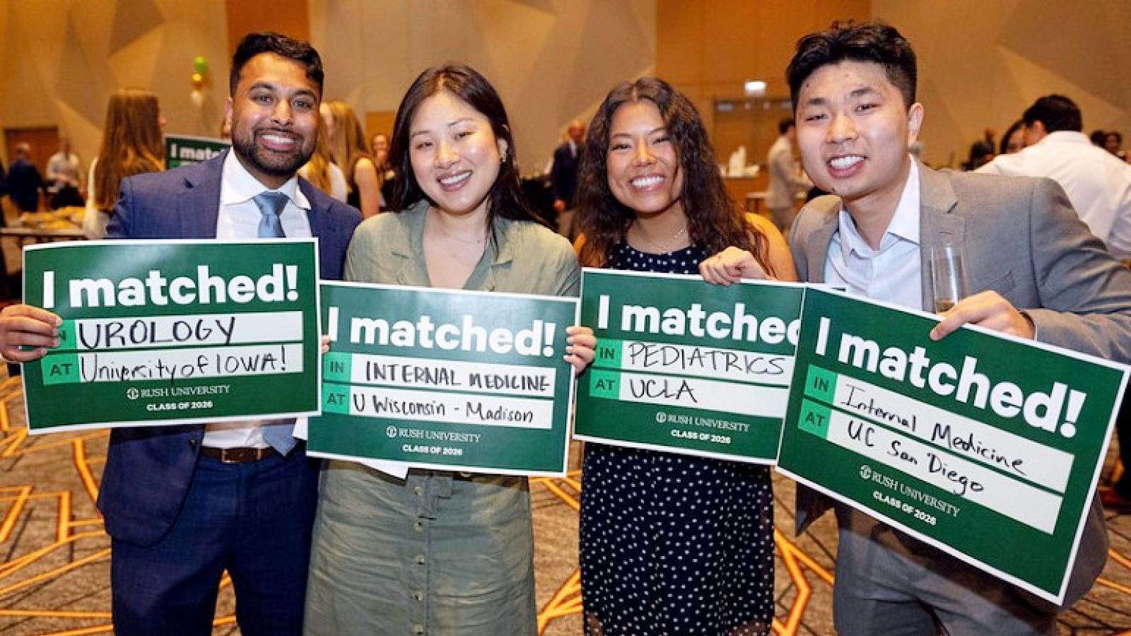 Four students smile and hold up signs saying I Matched