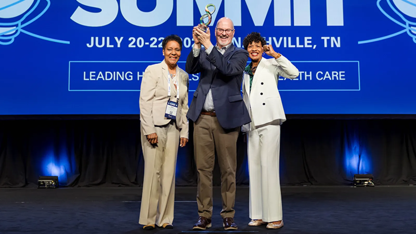 award recipients standing on stage in front of a blue background
