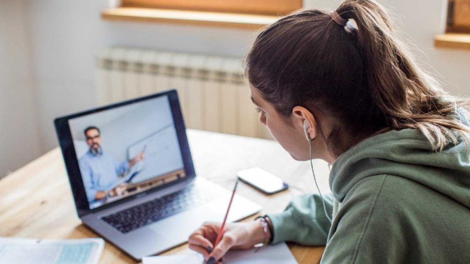 A student taking notes while viewing an online lecture