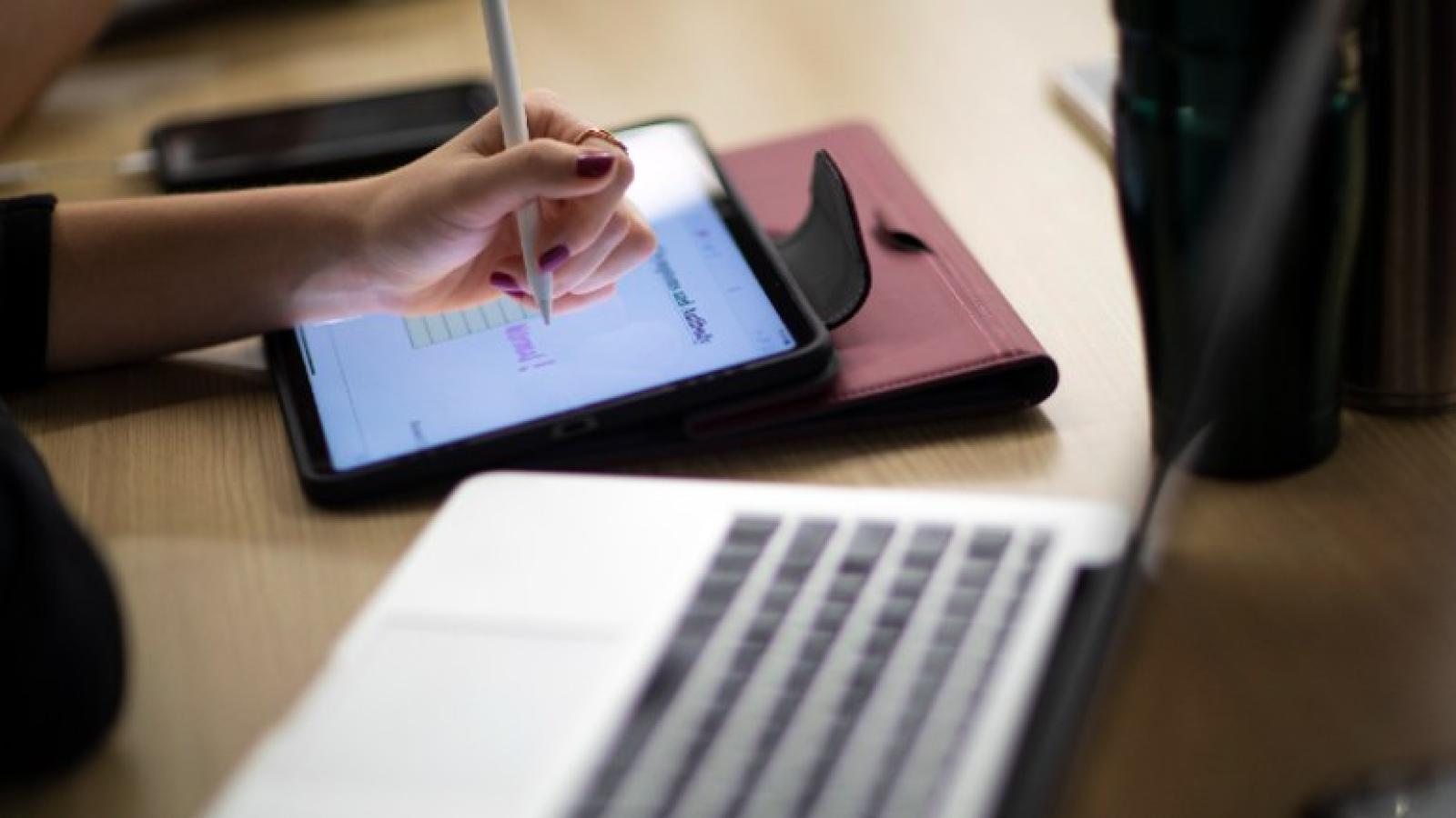 Student using a tablet with stylus and a laptop for online learning