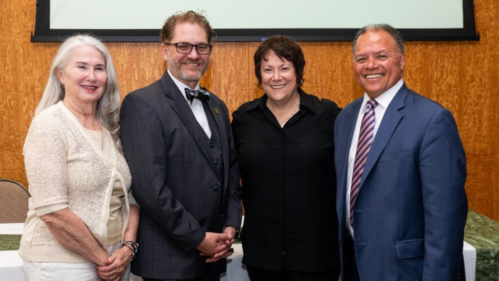 Four people stand together smiling