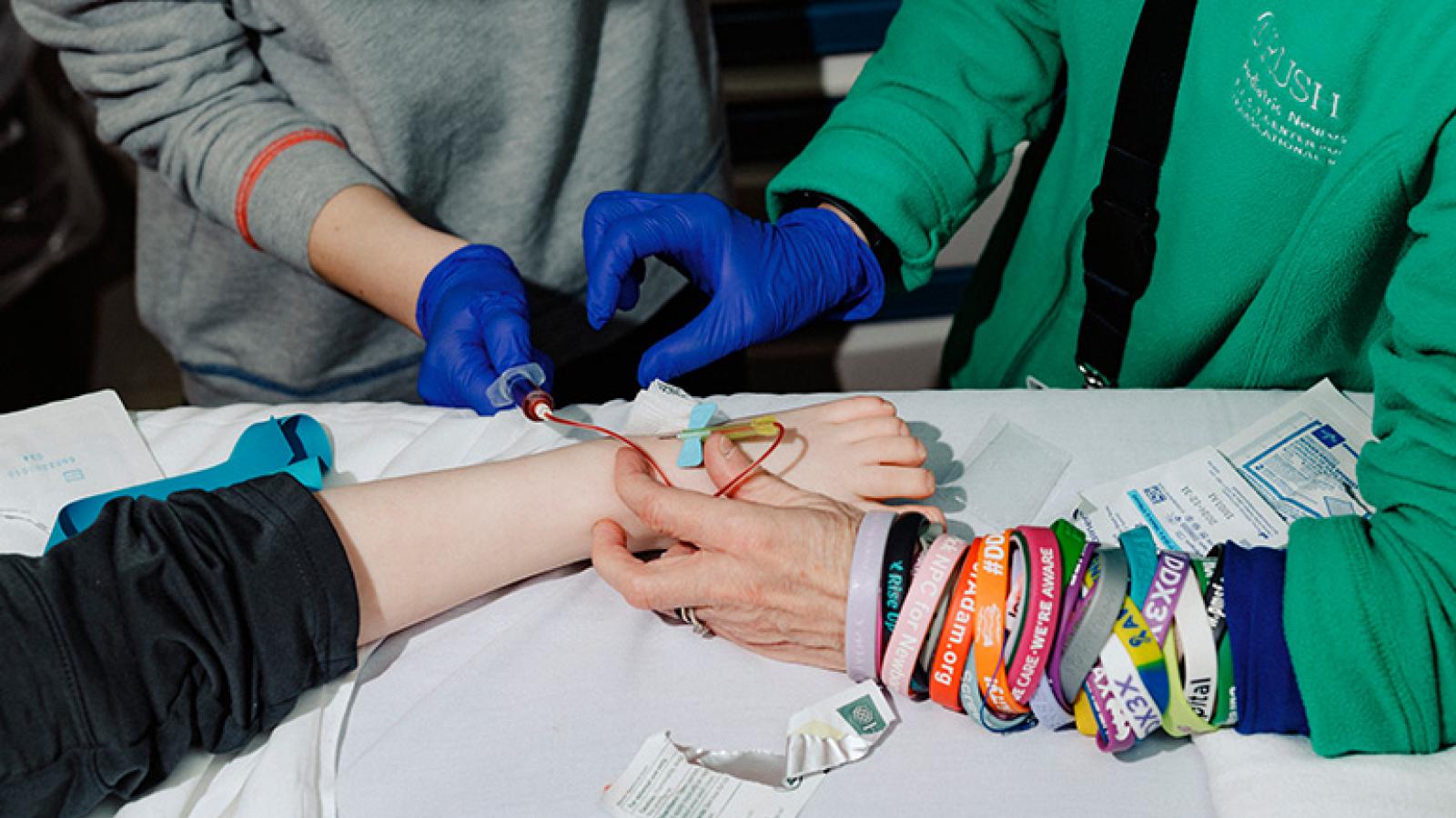 photograph showing the arms of two people administering an infusion to someone