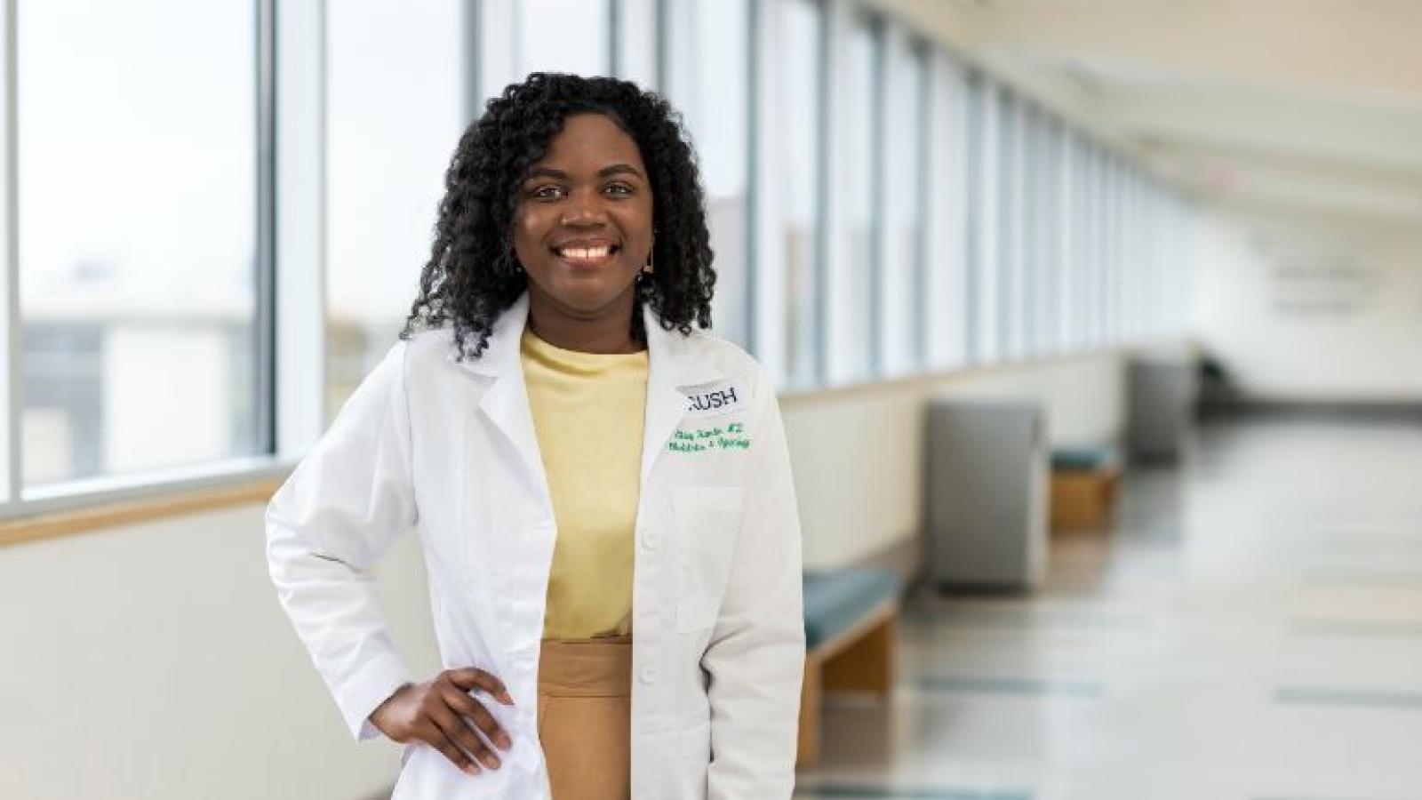 A smiling doctor standing by windows in a corridor