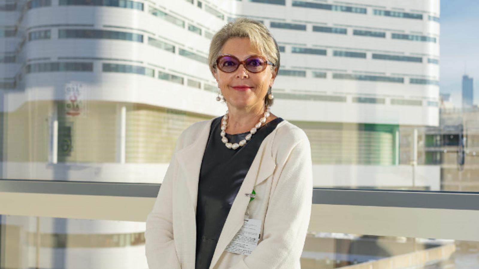 Smiling woman wearing a white coat with Rush Tower building visible in background