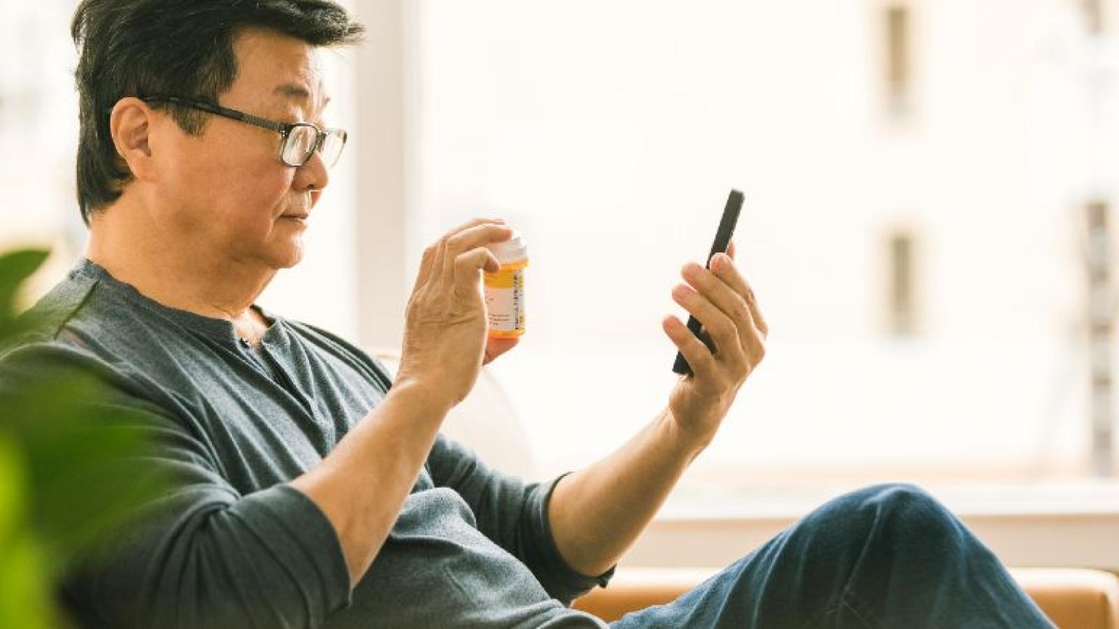 A man holds up a prescription bottle to show on a video call