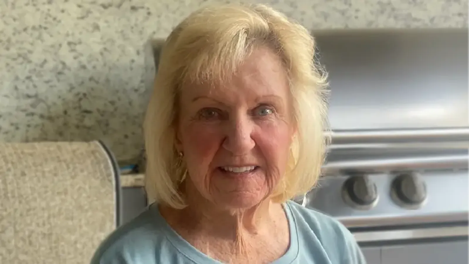 Patient Ulema Hirsch sits on a patio in front of a grill.