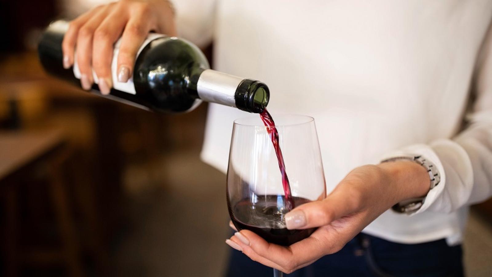 A woman pouring a glass of red wine