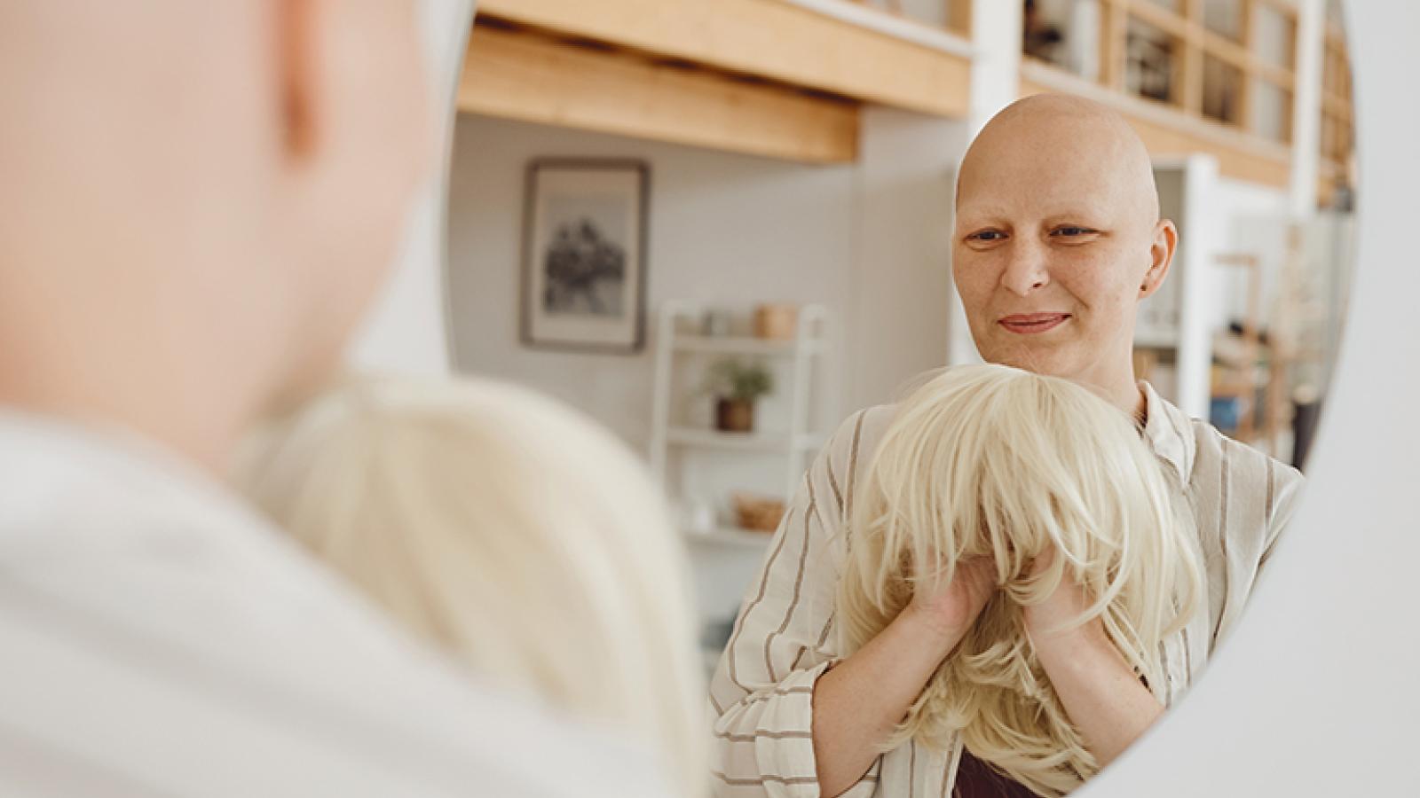 Woman looking in mirror holding wig