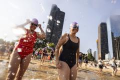 Two participants in Swim Across America's Chicago Open Water Swim splash in the water at Ohio Street Beach.